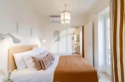 a bedroom with a bed with white walls and a chandelier at 2 pièces vieux Nice vue coulée verte in Nice