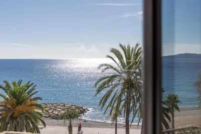 a view of a beach with palm trees and the ocean at Luxury apartment with sea view on the first line Promenade des Anglais in Nice