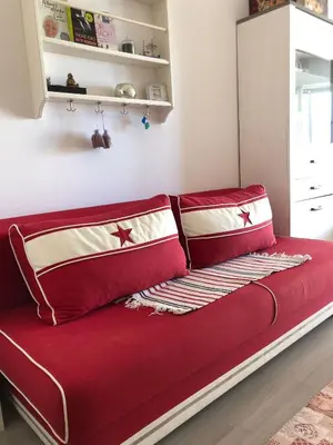 a red couch with two pillows on it in a room at Charmant studio à Cros de Cagnes in Cagnes-sur-Mer