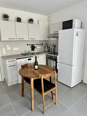 a kitchen with a wooden table and a white refrigerator at Charmant Studio à proximité du Port de Nice in Nice