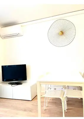 a white dining room with a table and a tv at Residence Californie in Nice