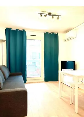 a living room with blue curtains and a table and a couch at Residence Californie in Nice