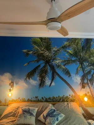 a bedroom with a ceiling fan and a palm tree mural at Appartement Nice CENTRE vue Mer avec piscine pour FAMILLE, couple d'amis pas de groupes de jeunes autorisés in Nice