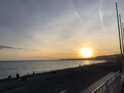 a sunset on a beach with the sun setting at Charming studio mezzanine w/ large terrace - Nice in Nice