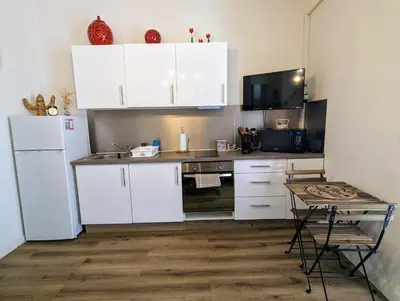 a kitchen with white cabinets and a table in it at Appartement cosy proche du port in Nice