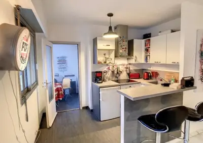 a kitchen with white cabinets and black stools in it at Superbe Studio tout équipé/Proche mer et commodité in Saint-Laurent-du-Var