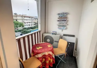a balcony with a table and chairs and a window at Superbe Studio tout équipé/Proche mer et commodité in Saint-Laurent-du-Var