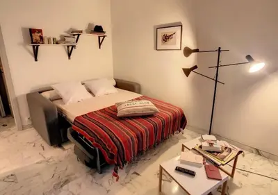 a small bedroom with a bed and a table at Superbe Studio tout équipé/Proche mer et commodité in Saint-Laurent-du-Var