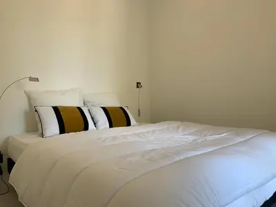 a white bed with black and white pillows on it at T2 Carré D'Or in Nice