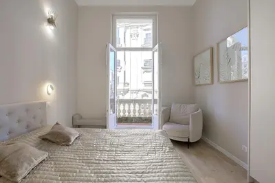 a bedroom with a bed and a chair and a window at Maison Bianchi - Clemenceau in Nice