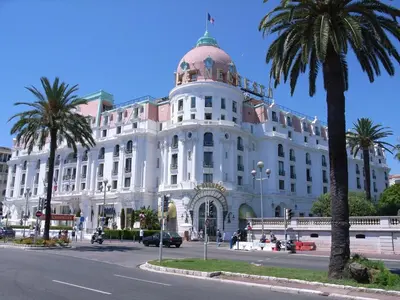 a large white building with palm trees in front of it at A Luxurious Apartment with AC on Promenade des Anglais in Nice