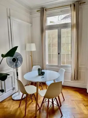 a white table and chairs in a room with a window at A Luxurious Apartment with AC on Promenade des Anglais in Nice