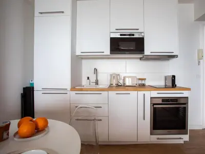 a kitchen with white cabinets and a table with oranges at Apartment L'Angelina-2 by Interhome in Cagnes-sur-Mer