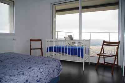 a bedroom with a bed and two chairs and a balcony at 3 pièces dans le ciel in Gattières
