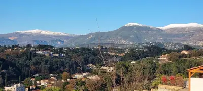 a mountain view of a town with snow covered mountains at 2 pièces calme et fonctionnel in Cagnes-sur-Mer