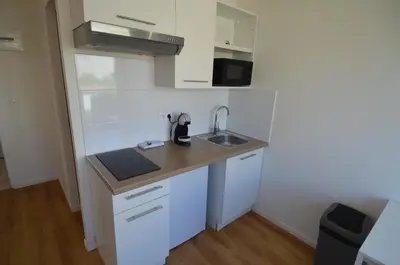 a small kitchen with white cabinets and a sink at STUDIO CASSIN - next to tramway line 2 near airport in Nice