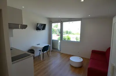a living room with a red couch and a window at STUDIO CASSIN - next to tramway line 2 near airport in Nice