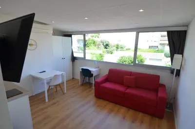 a living room with a red couch and a table at STUDIO CASSIN - next to tramway line 2 near airport in Nice