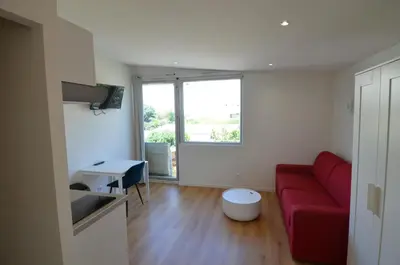 a living room with a red couch and a window at STUDIO CASSIN - next to tramway line 2 near airport in Nice