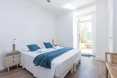 a white bedroom with a large bed with blue pillows at MY CASA - PONCHETTES - Independent House Promenade Des Anglais in Nice