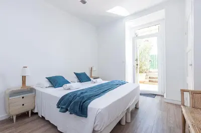 a white bedroom with a large bed with blue pillows at MY CASA - PONCHETTES - Independent House Promenade Des Anglais in Nice