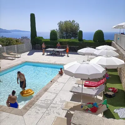 a group of people in a swimming pool with umbrellas at EXCEPTIONNEL 4 pieces vue panoramique baie des anges proche plage in Nice