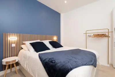 a bedroom with a large bed with a blue wall at Modern Apartment - Promenade des Anglais in Nice in Nice