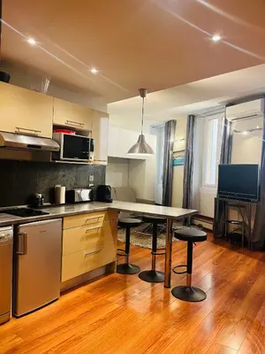 a kitchen with a table and two stools in it at Vieux Nice 2 pièces Appartement MONACO in Nice