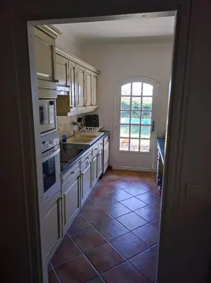 a kitchen with white cabinets and a tile floor at Villa Olivaie St Ange in La Gaude