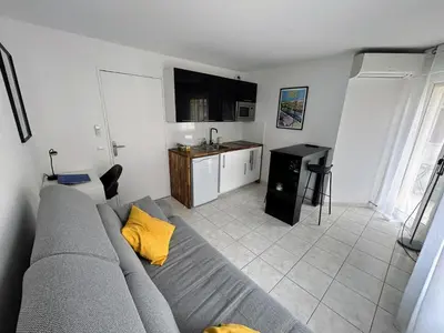 a living room with a gray couch and a kitchen at Magnifique studio au bord de mer in Nice