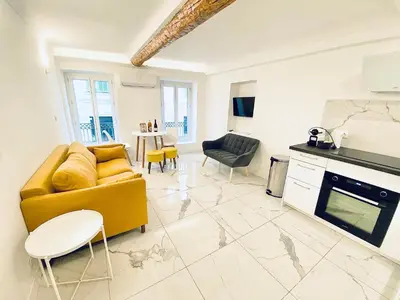 a living room with a yellow couch and a kitchen at T3 carré d’or plein centre in Nice