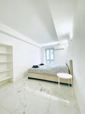 a white bedroom with a bed and a table at T3 carré d’or plein centre in Nice