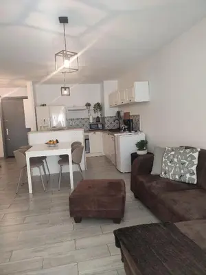a living room and kitchen with a couch and a table at Superbe appartement avec piscine l'été de juin à septembre in Nice