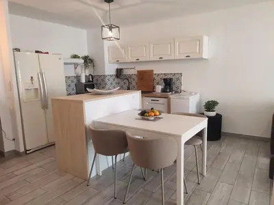 a kitchen with a white table and chairs and a white refrigerator at Superbe appartement avec piscine l'été de juin à septembre in Nice