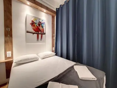 a bedroom with a bed and a blue curtain at Nestor&Jeeves - LE NICOIS - Central in Nice