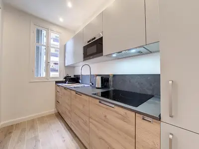 a kitchen with wooden cabinets and a black counter top at Nestor&Jeeves - LE NICOIS - Central in Nice