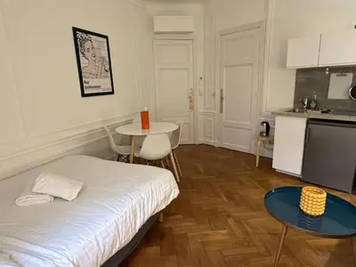 a room with a bed and a table and a kitchen at Luxurious 2 bedrooms on Promenades des Anglais in Nice