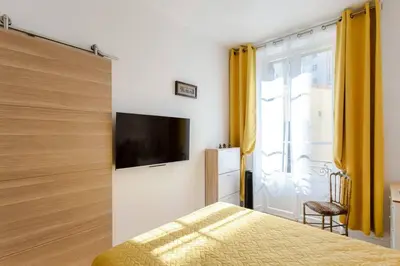 a bedroom with a bed with yellow curtains and a tv at L6 2Rooms 2mins walk from Negresco & Sea AC-Wifi in Nice