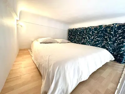 a bedroom with a white bed with a black headboard at Studio mezzanine sur le port in Nice