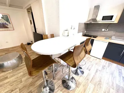 a kitchen with a white table and some chairs at Studio mezzanine sur le port in Nice