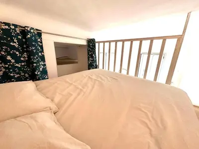 a bed with a white comforter in a room at Studio mezzanine sur le port in Nice