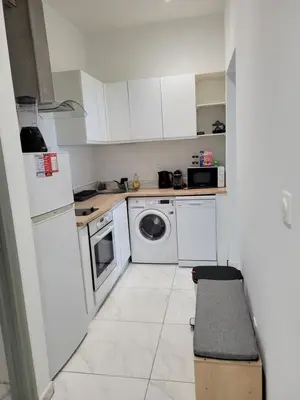 a kitchen with white cabinets and a washer and dryer at 2 pièces promenade des anglais in Nice