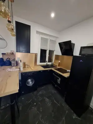 a kitchen with blue cabinets and a black refrigerator at Appartement tout confort, agréable à vivre in Nice