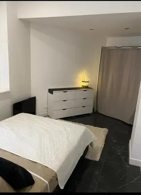 a bedroom with a white bed and a dresser at Appartement tout confort, agréable à vivre in Nice
