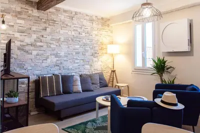 a living room with a blue couch and a brick wall at L16 Suite Malonat Vieux Nice 1 min Mer/ 2 chbres & AC in Nice