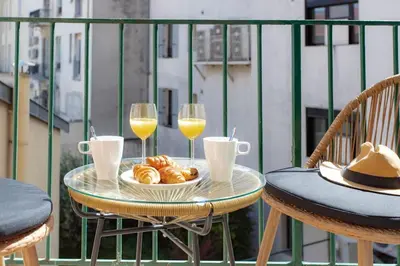 a table with two glasses of wine and pastries on a balcony at L19 1BDR Massena central 2mins Sea/PromenadeAC/Balcony in Nice