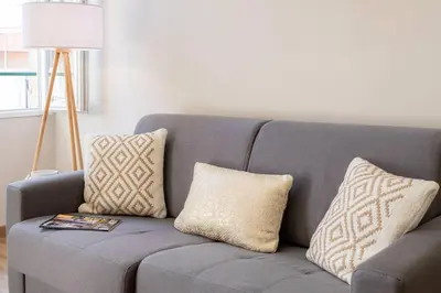 a gray couch with pillows and a lamp in a living room at L19 1BDR Massena central 2mins Sea/PromenadeAC/Balcony in Nice