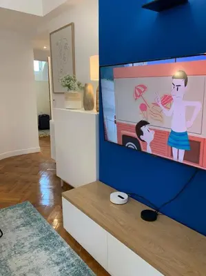 a living room with a tv with a picture of a boy at L24 Meyerbeer Promenade 1min SEA & Negresco AC/Balcony in Nice