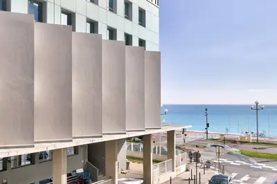 a view of a building with the ocean in the background at L29 Lenval beach at 1min walk to Sea front AC Balcony in Nice