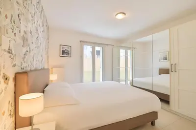 a white bedroom with a large bed and two lamps at Joli 2 pièces Niçois avec terrasse ensoleillée in Nice